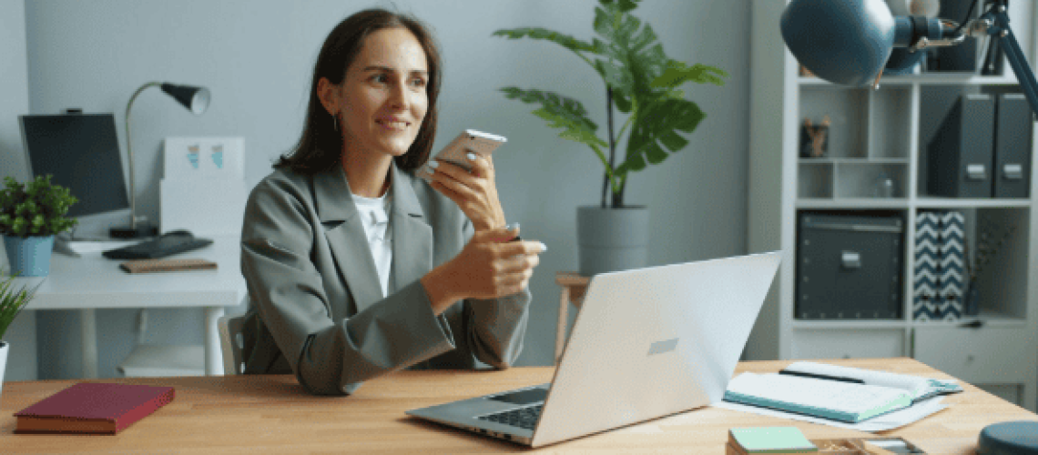 lady holding phone while working on a laptop