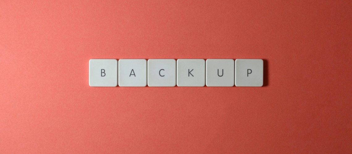 Simple-Backup-and-Recovery-Plans-Every-Small-Business-Needs-scaled.jpg Free Close-up of keyboard keys spelling 'BACKUP' placed on a coral-colored surface. Stock Photo