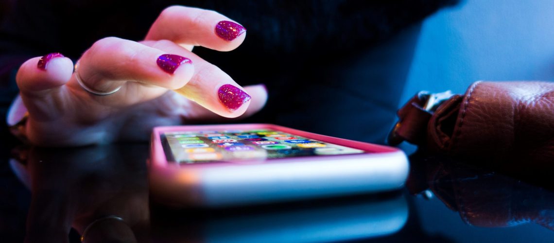 person using black smartphone with gray and pink case