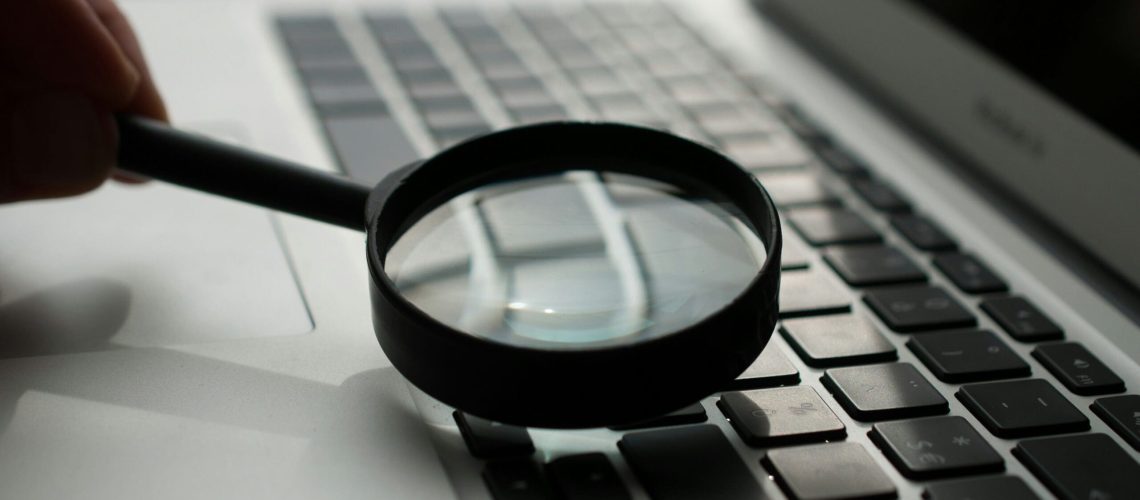 magnifying glass near gray laptop computer