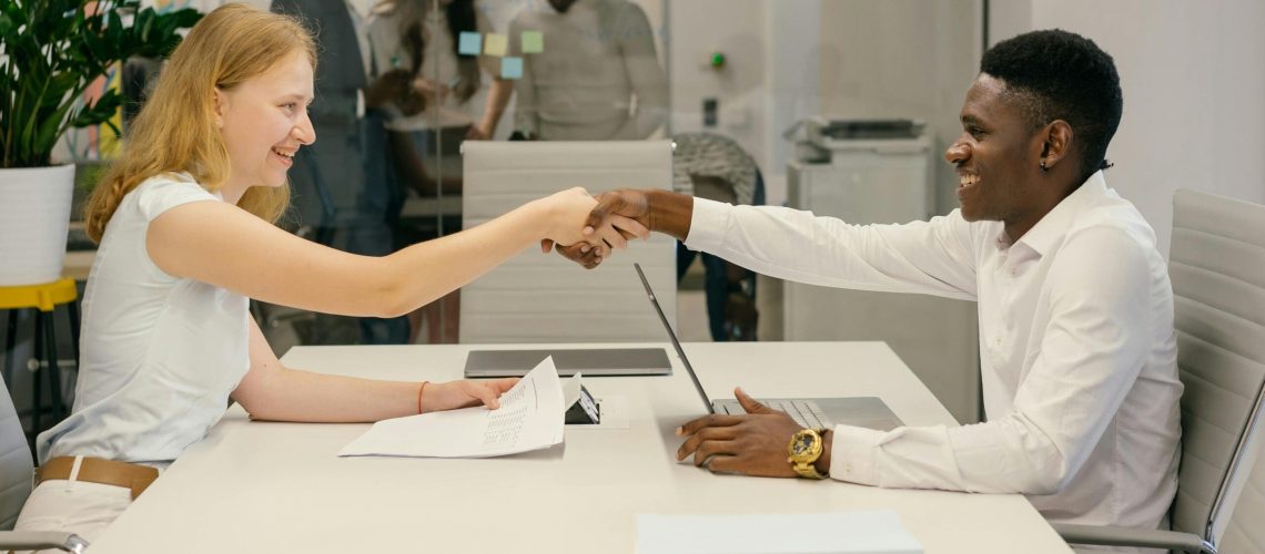 Free Business professionals completing a successful deal with a handshake in a modern office setting. Stock Photo
